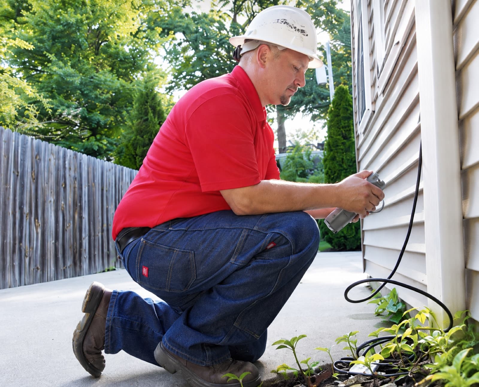 Illustrative scene of a technician working on exterior cabling beside a home